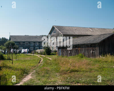 Rurales en bois maisons à deux étages avec une extension d'une porcherie sont sur une pelouse verte et de linge de maison qui est séché à l'extérieur sur des cordes sur une journée ensoleillée dans un vill Banque D'Images