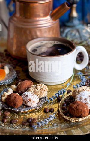 La cafetière se verse le café dans la tasse. dans un style oriental. bonbons artisanaux, fruits secs et de fleurs. dans le style d'art de l'obscurité. et de la céramique. Banque D'Images