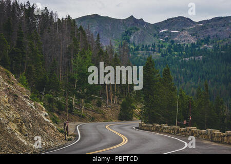 Vue panoramique de Trail Ridge Road serpentant à travers le Parc National des Montagnes rocheuses entourées d'arbres avec des montagnes en arrière-plan Banque D'Images