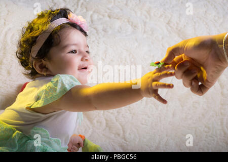 Mère de donner un peu de fleur en plastique de petite fille en face de couverture blanche. Banque D'Images