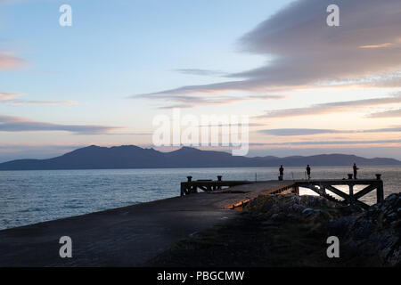 Portencross Jetty et Arran brumeuses Montagnes au coucher du soleil avec les pêcheurs à la fin de la jetée. Les pêcheurs sont dans la silouette Banque D'Images