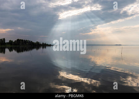 Parfaitement symétrique et vue spectaculaire d'un lac, avec des nuages, le ciel et les rayons du soleil reflétant sur l'eau Banque D'Images