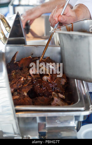 Une louche de sauce barbecue huckleberry adjudication des côtes de porc cuites lors d'une célébration. Banque D'Images