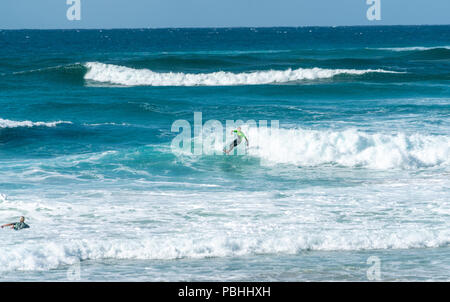COOLANGATTA, AUSTRALIE - juillet10 2018 ; Large plage de surf surfer avec équitation à travers l'onde blanc avec mousse de mer turquoise profond derrière Banque D'Images