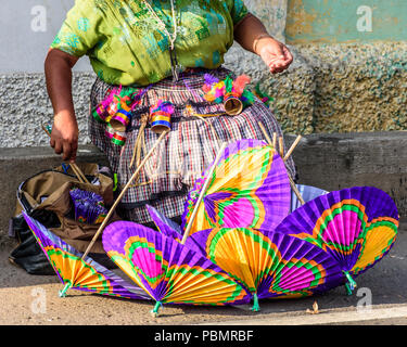 Ciudad Vieja, Guatemala - 7 décembre 2016 : indigènes Mayas femme portant chemisier traditionnel huipil appelé papier fait main vend parasols en rue. Banque D'Images