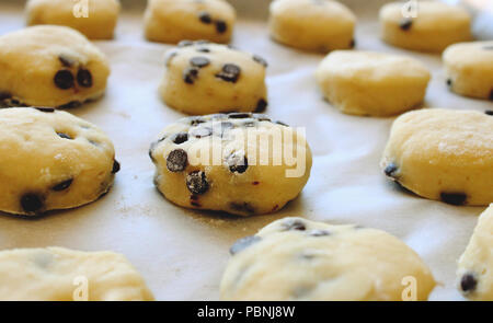 Close up of cookies au chocolat fait maison / biscuits sur du papier sulfurisé prêtes pour le four Banque D'Images