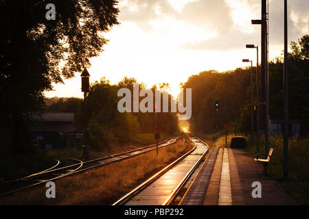 La fin de l'après-midi du soleil se reflète sur les rails à côté de la plate-forme à la petite gare de Quelle, près de Halle (Westfalen), Allemagne. Banque D'Images