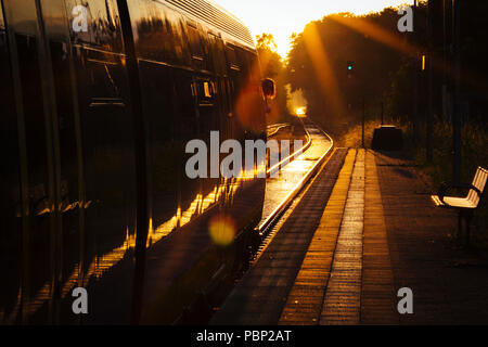 La fin de l'après-midi du soleil se reflète sur un train en arrivant à la petite gare de Quelle, près de Halle (Westfalen), Allemagne. Banque D'Images