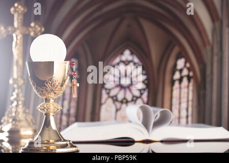 Église catholique romaine thème. La Croix, la Sainte Bible, Rosaire et Golden Chalice sur l'autel. Banque D'Images