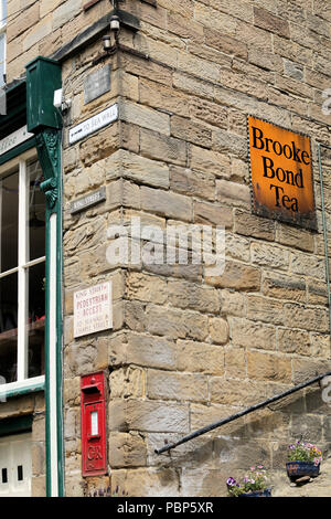 Coin de l'ancien bâtiment du bureau de poste, dans la rue King, Robin Hood's Bay, montrant post box et l'émail thé Brooke Bond enseigne publicitaire Banque D'Images