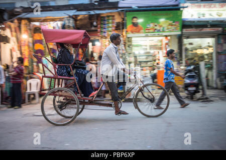 Location de vélo-taxi essaie de pousser un client à travers les rues bondées du centre de New Delhi. Banque D'Images