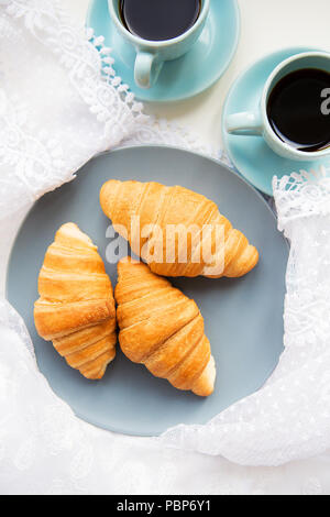 Deux tasses de café avec les croissants sur l'arrière-plan de lacets Banque D'Images