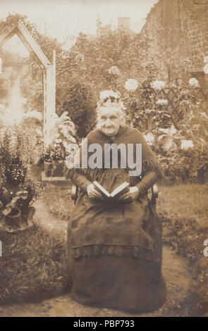 Vintage Photo d'une vieille dame de 90 ans La lecture dans son jardin Banque D'Images