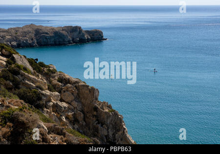 Belle vue de l'île de Rhodes dans la Méditerranée avec deux touristes non identifiés dans la distance engagé standup paddleboarding Banque D'Images