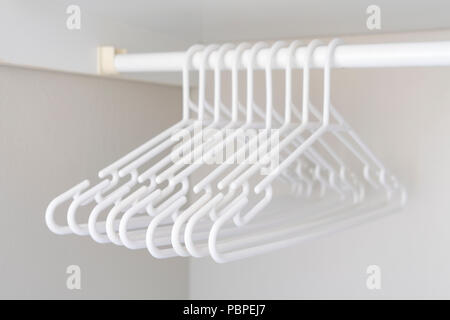 Bande de cintres en plastique blanc accroché à un porte manteau dans l'armoire Banque D'Images