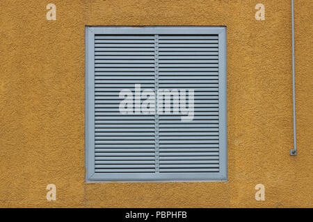 Une fenêtre dans un grand centre commercial industriel fermé avec stores extérieurs sous la forme de grilles de ventilation. orange jaune beige background, relie Banque D'Images