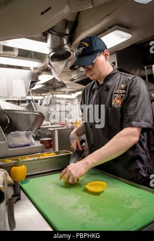 180725-N-SO730-0005 Norfolk, en Virginie (25 juillet 2018) 3ème classe spécialiste culinaire Zachary Cochran, de Trenton, New Jersey, prépare des poivrons jaunes pour un bar à salades à être servis dans le cadre d'un déjeuner à bord du porte-avions USS George H. W. Bush (CVN 77). Le bateau est dans le port de Norfolk, Virginie, en effectuant des exercices d'entraînement de routine pour maintenir l'état de préparation de l'opérateur. (U.S. Photo par marine Spécialiste de la communication de masse 3e classe Joe Boggio) Banque D'Images