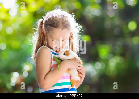 Enfant jouant avec cobaye. Les enfants se nourrissent les animaux. cavia Little girl holding et l'alimentation des animaux domestiques. Les enfants prennent soin des animaux domestiques. Enfant d'âge préscolaire pe Banque D'Images