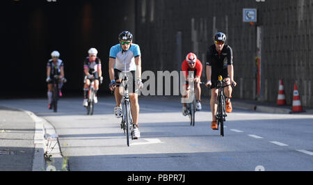 Hambourg, Allemagne. 29 juillet, 2018. Le Triathlon, Ironman World Series : triathlètes circonscription leurs vélos à travers le Wallring Tunnel. Crédit : Daniel Reinhardt/dpa/Alamy Live News Banque D'Images