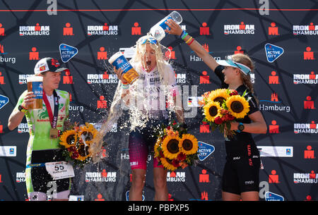 29 juillet 2018, l'Allemagne, Hambourg, triathlon, Ironman World Series : Premier placé Sarah Crowley (M) de l'Australie, deuxième placé Katharina Grohmann (l) d'Allemagne et troisième étape Maja Nielsen de Danemark cheer sur le podium. Photo : Daniel Reinhardt/dpa Banque D'Images