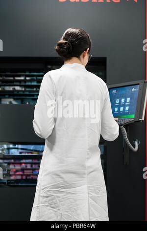 Pharmacien à l'aide d'un ordinateur tout en gérant le stock de médicaments en pharmacie Banque D'Images