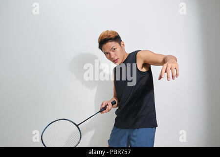 Handsome young man holding badminton raquette et volant sur gris Banque D'Images