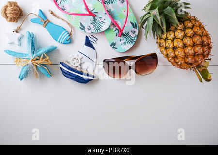 Été plage vacances avec des lunettes de soleil, les ananas, les tongs sur fond de bois blanc avec l'espace, vue d'en haut Banque D'Images