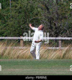 Un joueur lance la balle dans de la frontière dans un match de cricket entre Birch Vale et Thornsett deuxième équipe et Stalybridge St Paul's deuxième équipe. Banque D'Images