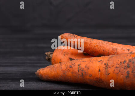 Sale Orange carottes sur fond sombre. Close up. Fond en bois noir. Banque D'Images