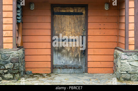 Bâtiment en bois rouge mur avec une vieille porte en bois patiné, Olympic Peninsula, WA, USA. Banque D'Images