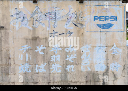 Logo Pepsi s'est évanouie et les caractères japonais sur mur de béton ; Ginowan, Okinawa Prefecture, Japan Banque D'Images