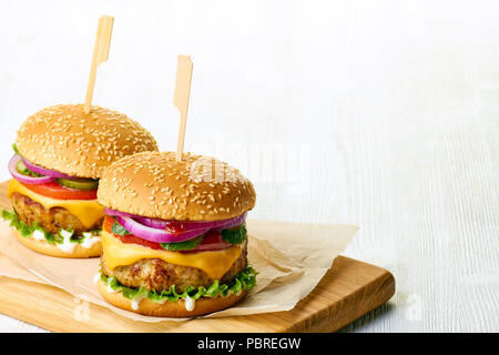 Deux délicieux cheeseburgers sur planche à découper en bois Banque D'Images