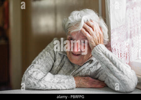 Femme âgée assise à la table. Banque D'Images