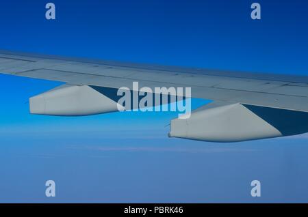 Jet avion/ aile (vue arrière), volant au-dessus des nuages, contre Deep Blue Sky de couleur. Tourné à partir d'une fenêtre d'un avion commercial. Banque D'Images