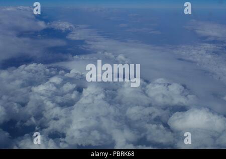 De beaux nuages blancs tourné à partir d'une fenêtre d'un avion commercial / vol à au-dessus d'eux, contre le ciel bleu, sur une belle journée ensoleillée. Banque D'Images