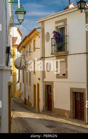 Hauts femme appuyée sur son fer à repasser balcon donnant sur les rues médiévales étroites de Castelo de Vide Portugal Banque D'Images