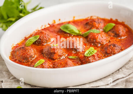 Des boulettes de viande en sauce tomate au basilic dans un plat blanc. Banque D'Images