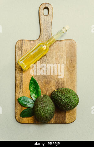 L'avocat et l'avocat feuilles et l'huile d'avocat dans une bouteille sur un fond de bois Banque D'Images