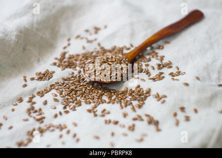 Lin dans une cuillère en bois, saupoudré sur une nappe de lin Banque D'Images