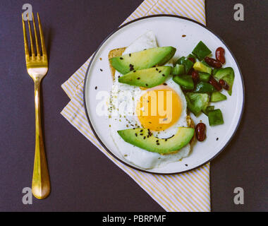 Un petit-déjeuner sain de toast à l'avocat, du pain de blé entier et œuf frit et salade burrito on white plate Banque D'Images