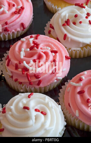 Délicieux cupcakes, recouvert de glaçage rose et blanc incandescent et sprinkles, juste à temps pour la Saint-Valentin. Savoureux, mais malheureusement aussi Banque D'Images