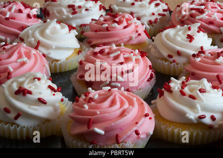 Délicieux cupcakes, recouvert de glaçage rose et blanc incandescent et sprinkles, juste à temps pour la Saint-Valentin. Savoureux, mais malheureusement aussi Banque D'Images