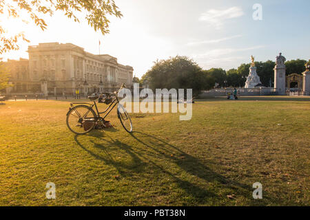 Une dame sonner pendant son vélo par l'extérieur de Buckingham Palace, sur l'herbe desséchée d'un été chaud Banque D'Images