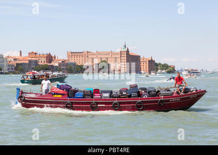 Les hommes sur un bateau de travail offrant une assurance d'un groupe de touristes, Giudecca Canal, Venice, Veneto, Italie. Bateau touristique chargé de bagages, sacs, valises transpor Banque D'Images