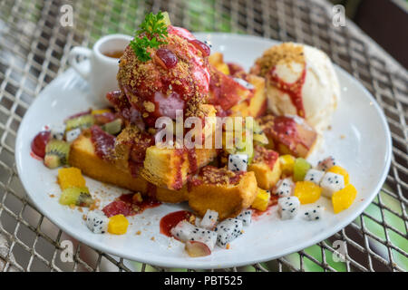 Assiette à dessert de miel pain grillé avec de la glace vanille, mélange de fruits en tranches, les tranches de mangue, kiwi, fruit du dragon et crème fouettée sur métal Banque D'Images