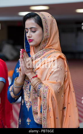 Un beau mariage guest prie et médite avant la cérémonie à un mariage sikh à Richmond Hill, Queens, New York. Banque D'Images