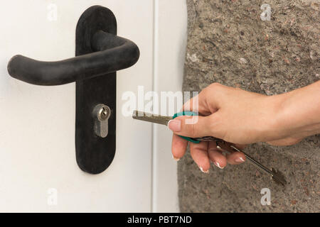 La fille ouvre la porte avec une clé, close-up Banque D'Images