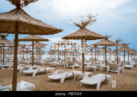 Des chaises longues avec des parasols de paille sur une belle plage Banque D'Images