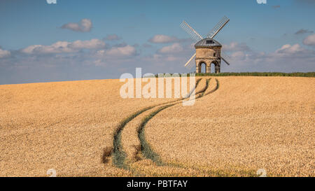 Un moulin à vent dans le soleil d'été. Situé en haut d'une colline et entourée de blé. Des marques de roues gauche tracteurs dans le domaine menant jusqu'à l'usine Banque D'Images