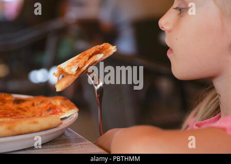 Cute little girl eating pizza savoureuse et délicieuse. Banque D'Images